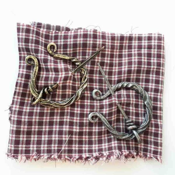 Two Fibulae with decorations in a piece of plaid fabric