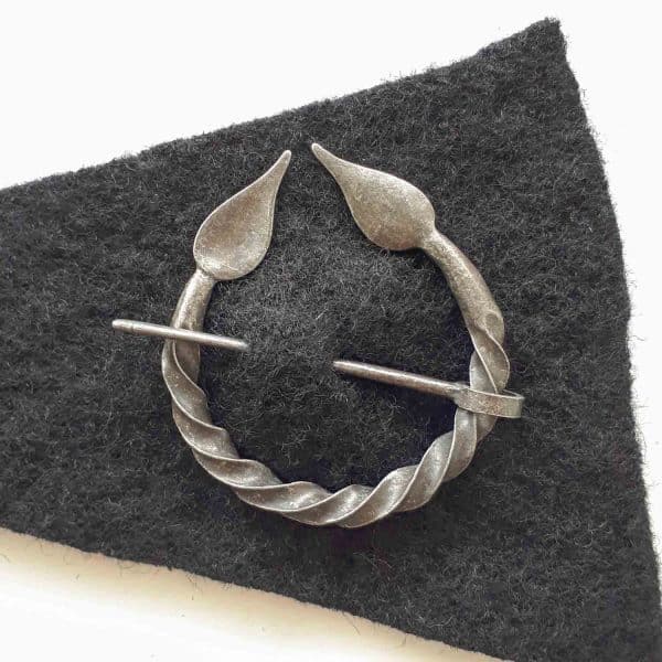 A twisted metal fibula with leaves in a piece of wool fabric