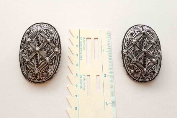 Viking brooches with shield design with a ruler showing the size