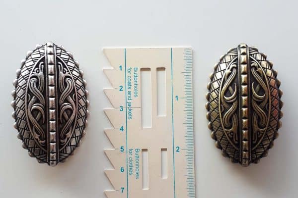 Viking brooches with dragons next to a ruler to show the size